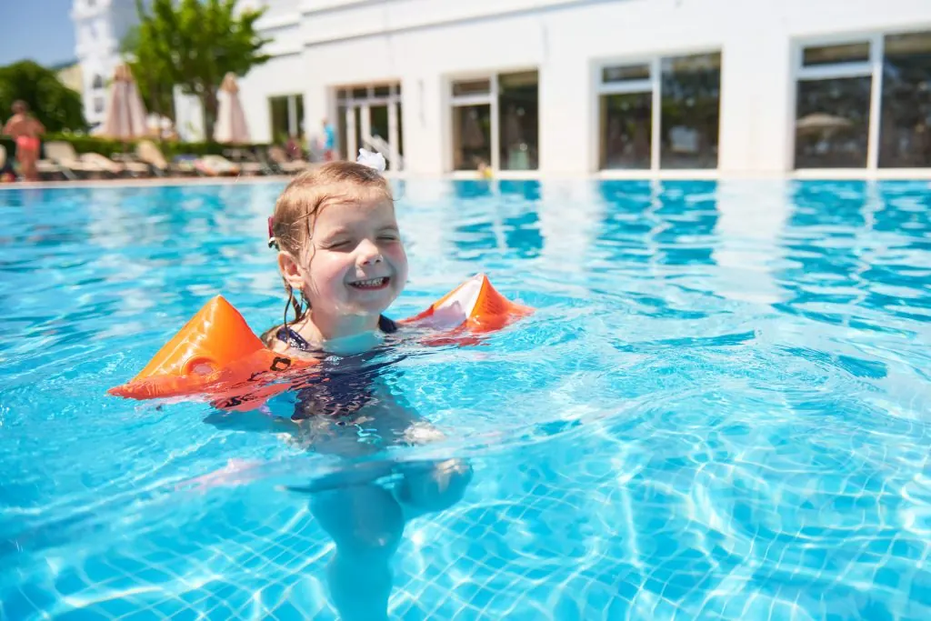 crianças Girl swimming in the pool in armlets on a hot summer day.